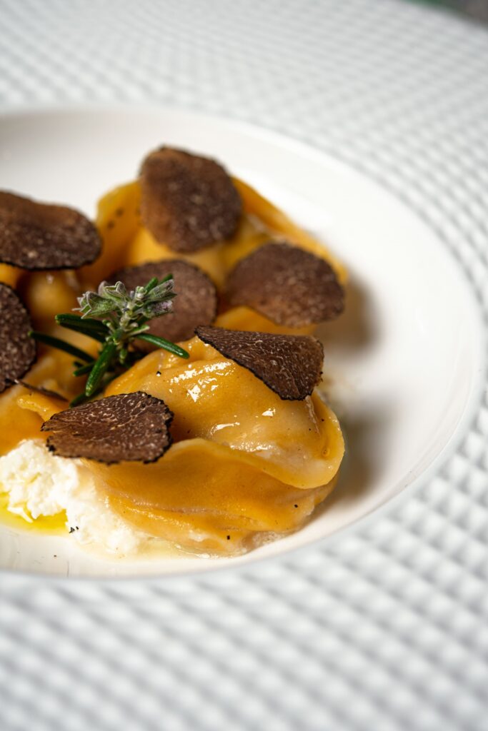 Cappelli di pasta farciti di pollo biologico alla genovese con fonduta di parmigiano e tartufo nero del Matese
